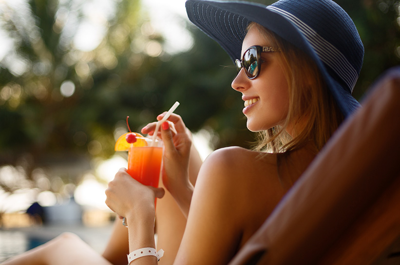 woman lounging by the pool with a cocktail